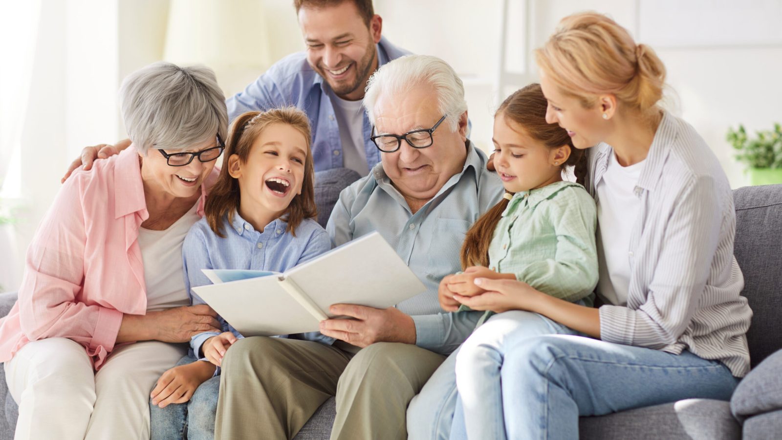 Happy big family, gathering at home on sofa, laughing three generations got printed album, viewing funny family life moments, enjoy photos remembering, photobook, parents, grandparents, children fun