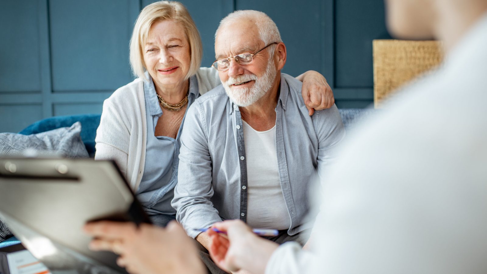 Happy senior couple during the meeting with agent or financial consultant, signing some agreement in the comfortable office