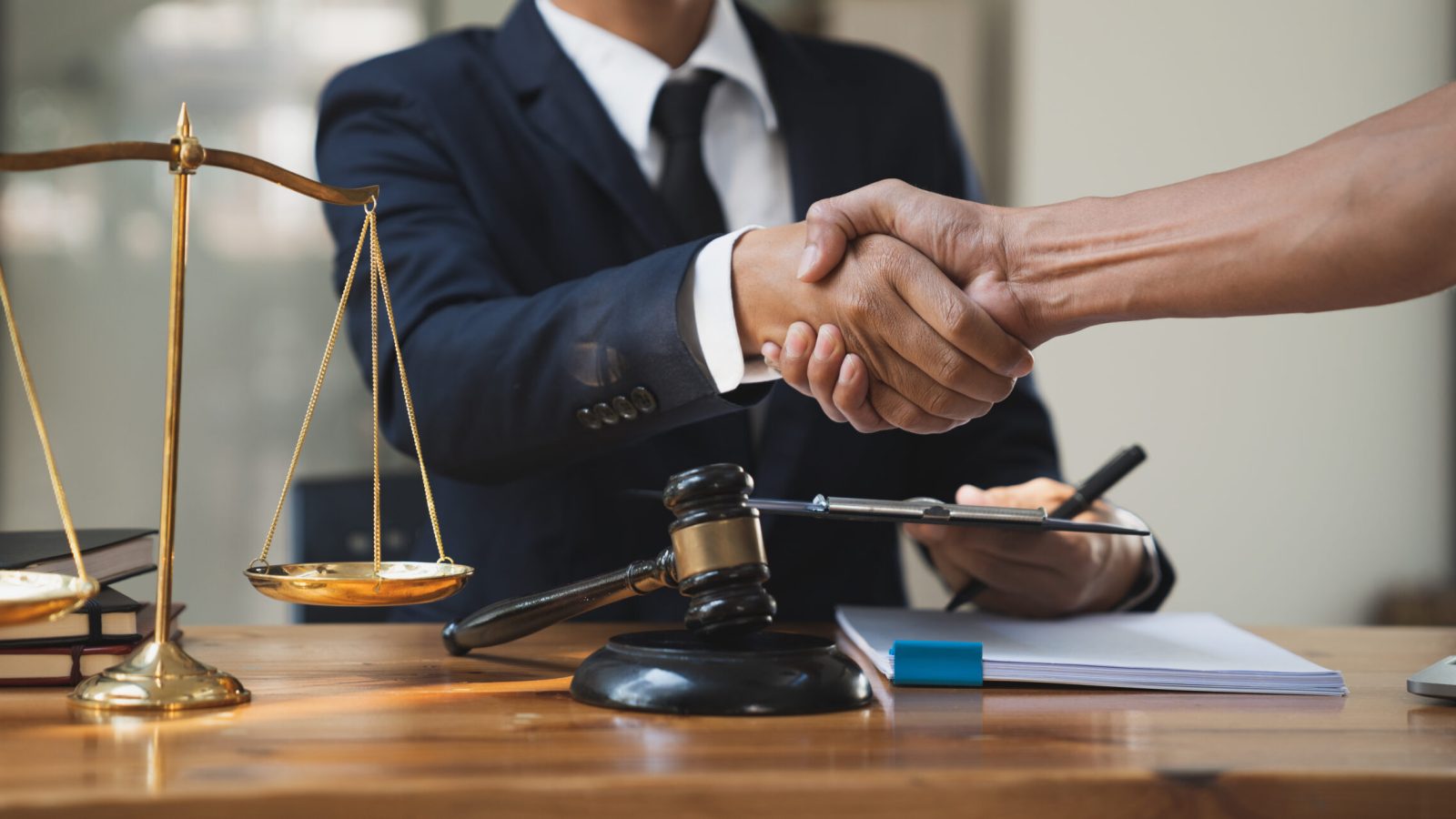 Legal concept - business team shaking hands with young Asian lawyer after agreeing on business cooperation agreement in office.