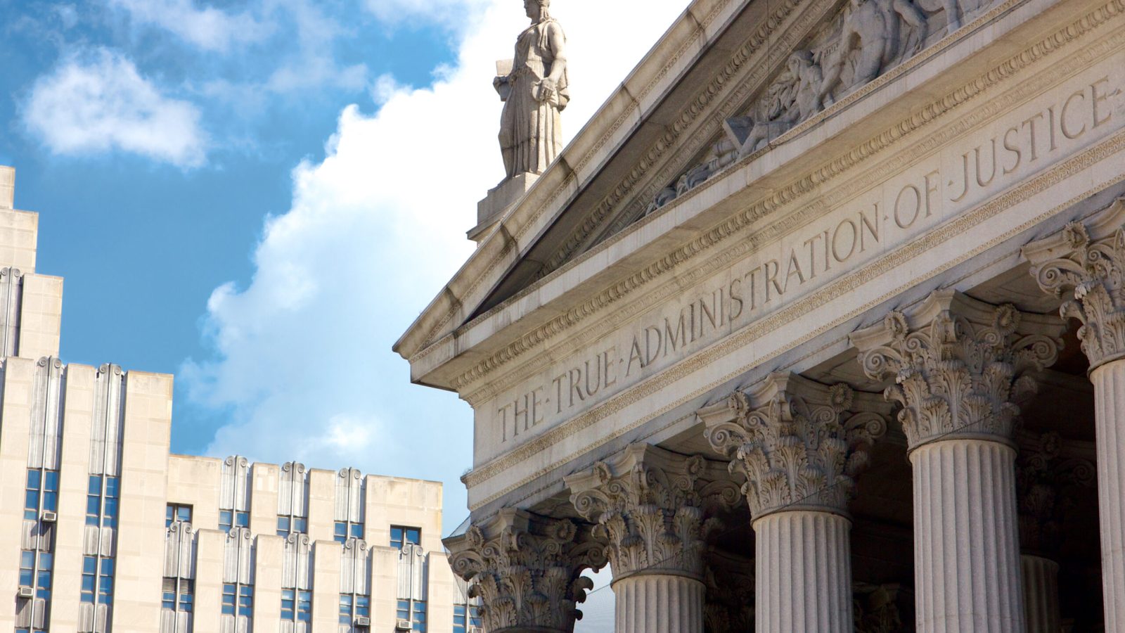New York State Supreme Court building in Lower Manhattan showing the words "The True Administration of Justice" on its facade in New York, NY, USA.